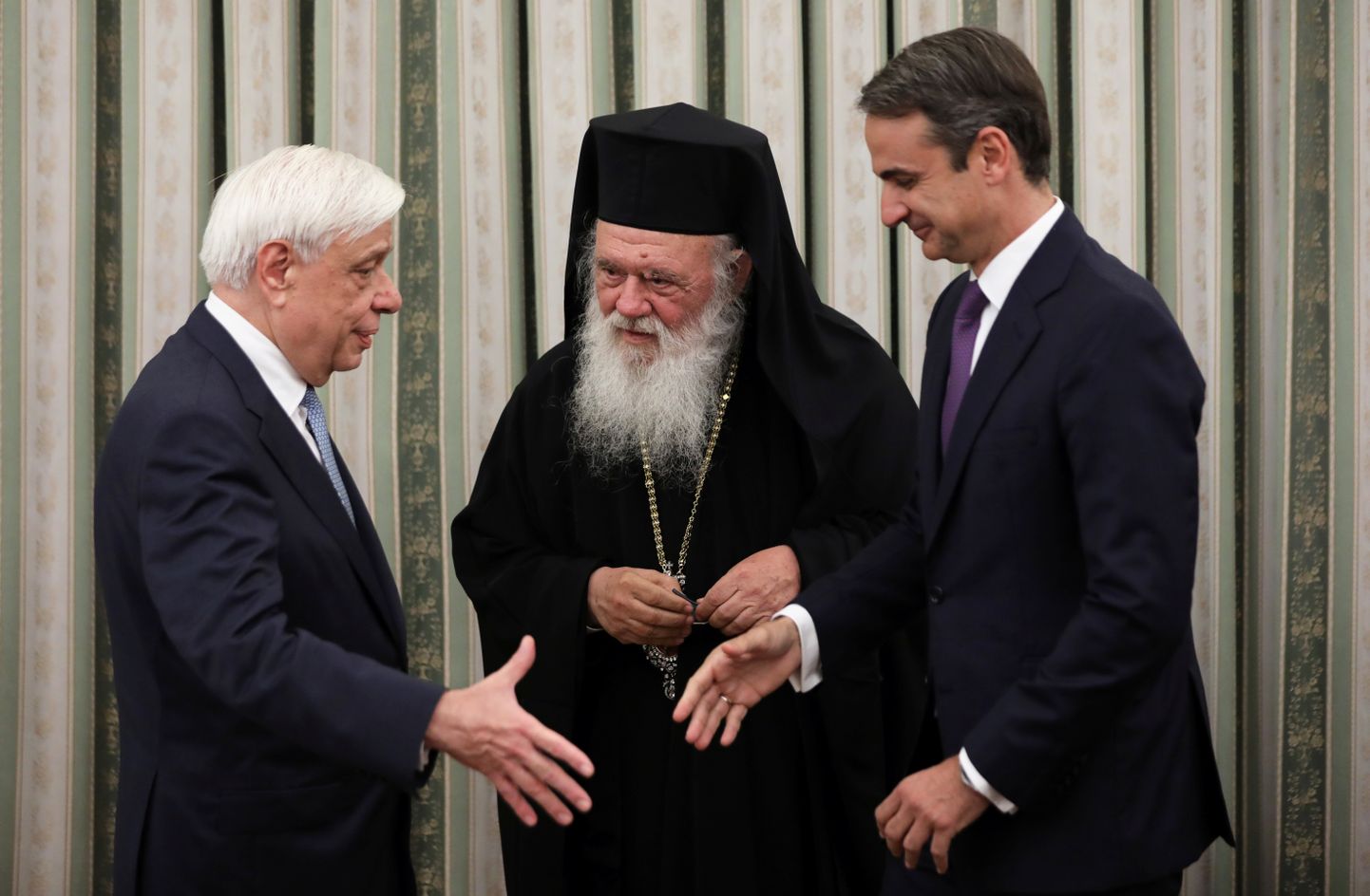 Kreeka uus peaminister Kyriakos Mitsotakis (paremal) surub kätt president Prokopis Pavlopoulosega. Keskel on peapiiskop Hieronymos.