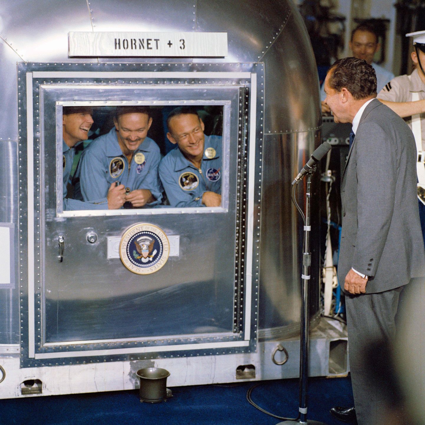 "Apollo 11" astronauti pārvietojamajā karantīnas kapsulā, tiekoties ar toreizējo ASV prezidentu Ričardu Niksonu.