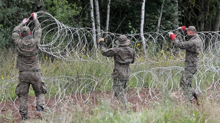 Польские солдаты протягивают колючую проволоку на границе с Беларусью.