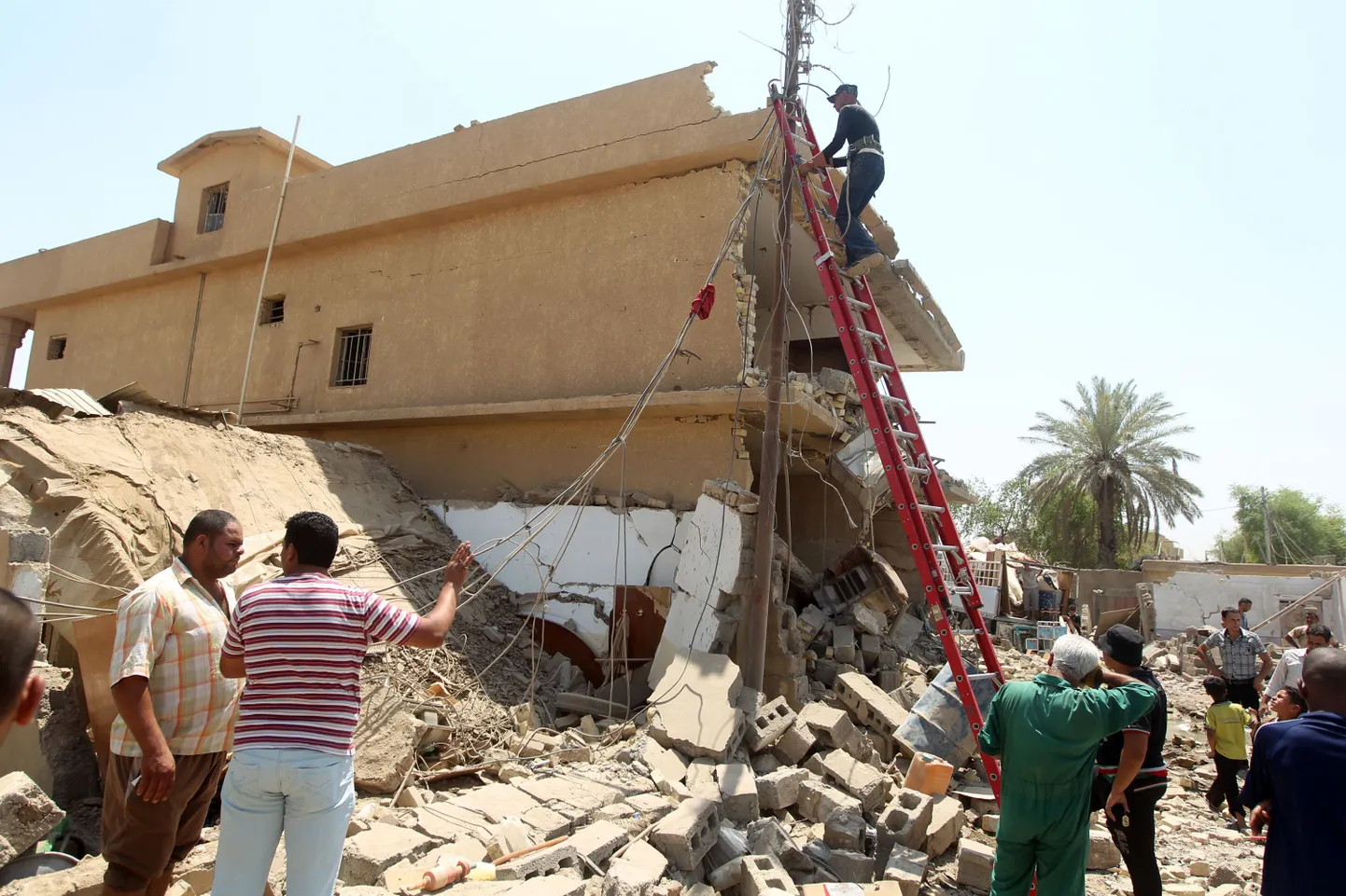 Taji linna elanikud pommiplahvatuses hävinud hoone ees.