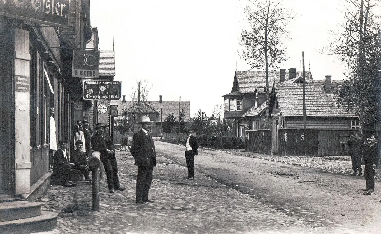 Seltskond Mõisaküla tee- ja söögimaja ees 1914. aastal. Kell on üheksa läbi ning söögimaja avatud. Taamal paistab rõduga Kollisti maja, kus 1905. aastal avati esimene Mõisaküla kool – Jaan Sihveri erakool.