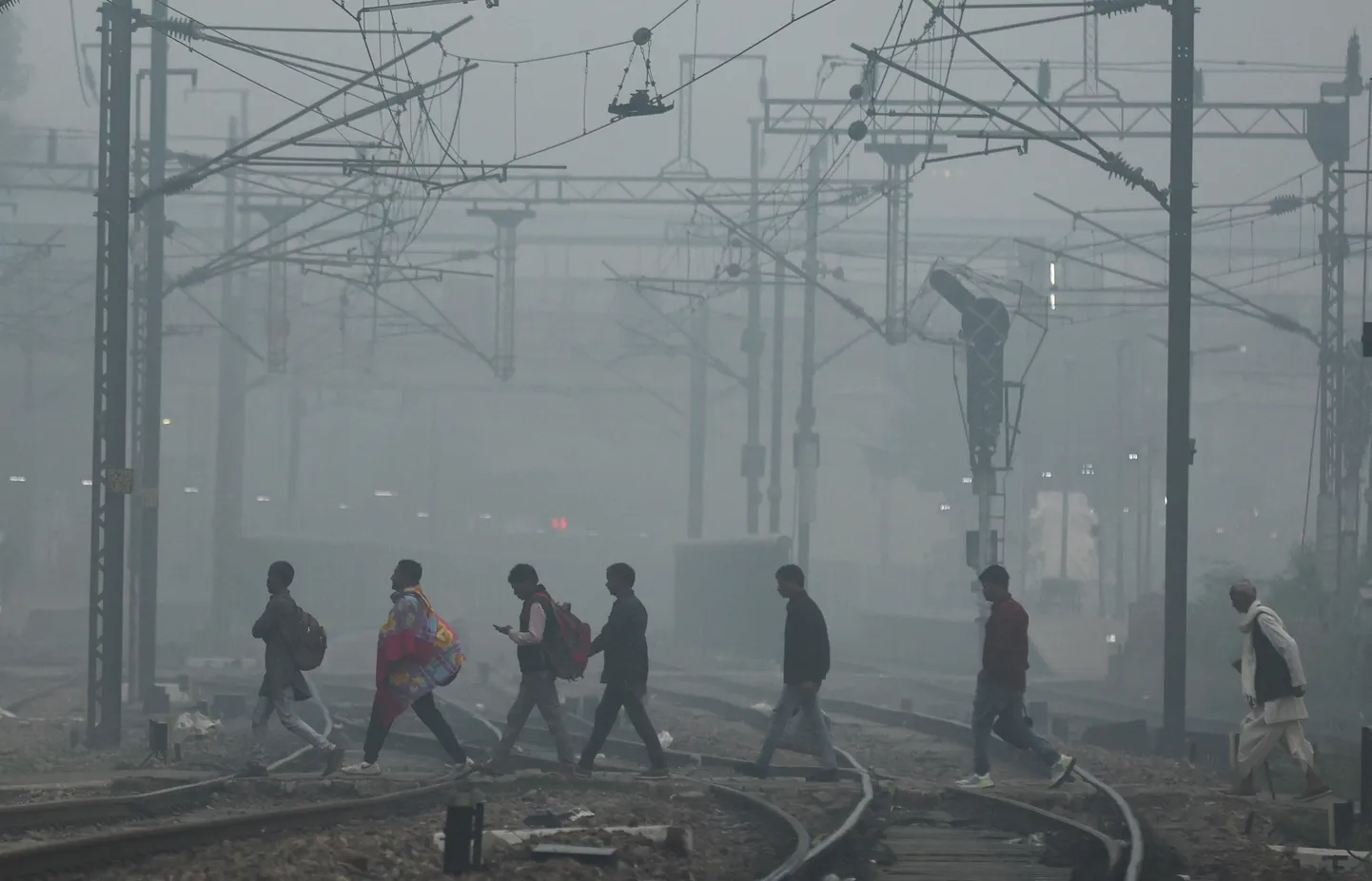 Delhi elanikud sudusel hommikul raudteed ületamas.